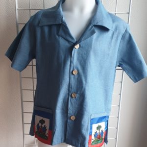 17.1 Chemise karabela tenue traditionnelle haïtienne de couleur bleue. Style ample. Deux poches latérales basses ornées chacune d'entre elles du drapeau Haïti. Cinq boutons non décoratifs centraux alignés de bas en haut de la chemise. Tissu 100% coton. Le col pouvant être surélevé selon le goût.