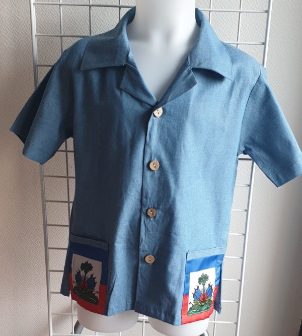 17.1 Chemise karabela tenue traditionnelle haïtienne de couleur bleue. Style ample. Deux poches latérales basses ornées chacune d'entre elles du drapeau Haïti. Cinq boutons non décoratifs centraux alignés de bas en haut de la chemise. Tissu 100% coton. Le col pouvant être surélevé selon le goût.