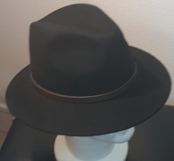 Chapeau en laine de couleur noire, doté d'un large bord et orné d'une petite ceinture en cuir marron, circulaire à sa base.