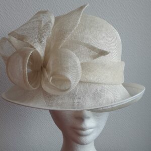 Chapeau de cérémonie de couleur ivoire 100% SINAMAY. Les réglages de ce couvre-chef se réalisent soigneusement à l'intérieur par cordon de serrage. Taille modulable. Prix :  69,95€.
