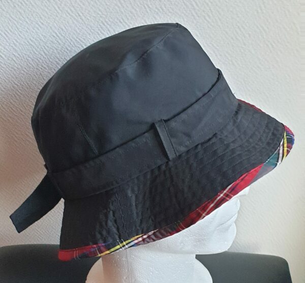 Bob unisexe de couleur noire imperméable et entièrement doublé en tissu polyester. Réglable à l'arrière par boucle de serrage. Finition biais écossais.