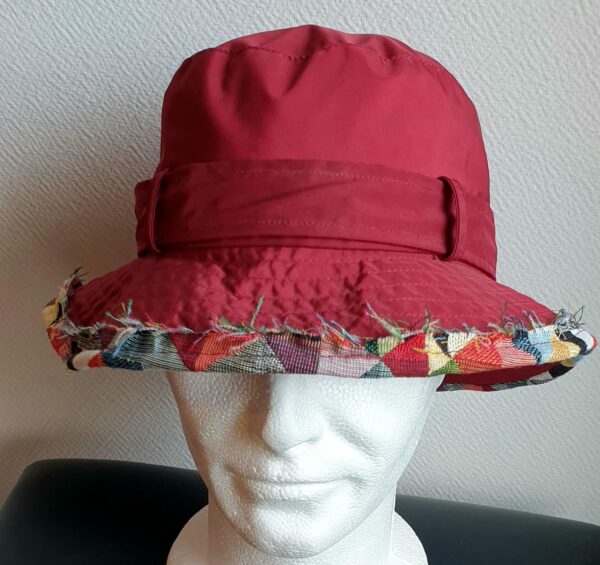 26.1Bob unisexe de couleur rouge grenat imperméable et entièrement doublé en tissu polyester. Réglable à l'arrière par boucle de serrage. Finition biais en coton. Taille 56. Prix 23.50€