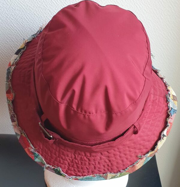 Bob unisexe de couleur rouge grenat imperméable et entièrement doublé en tissu polyester. Réglable à l'arrière par boucle de serrage. Finition biais en coton.