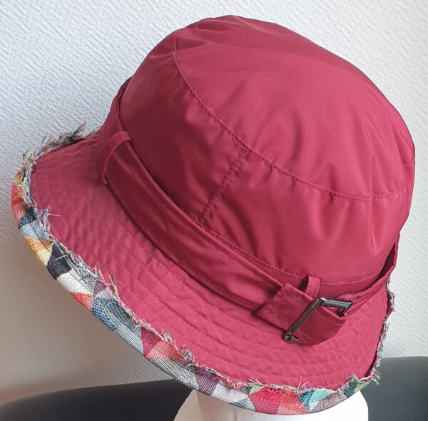 Bob unisexe de couleur rouge grenat imperméable et entièrement doublé en tissu polyester. Réglable à l'arrière par boucle de serrage. Finition biais en coton.