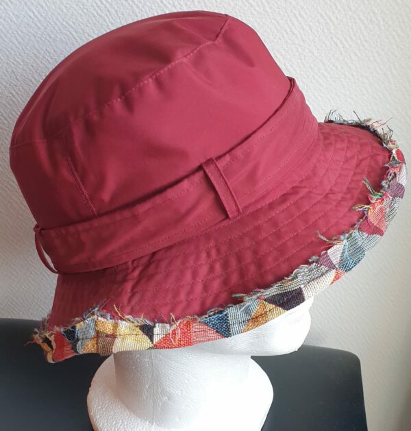 Bob unisexe de couleur rouge grenat imperméable et entièrement doublé en tissu polyester. Réglable à l'arrière par boucle de serrage. Finition biais en coton.