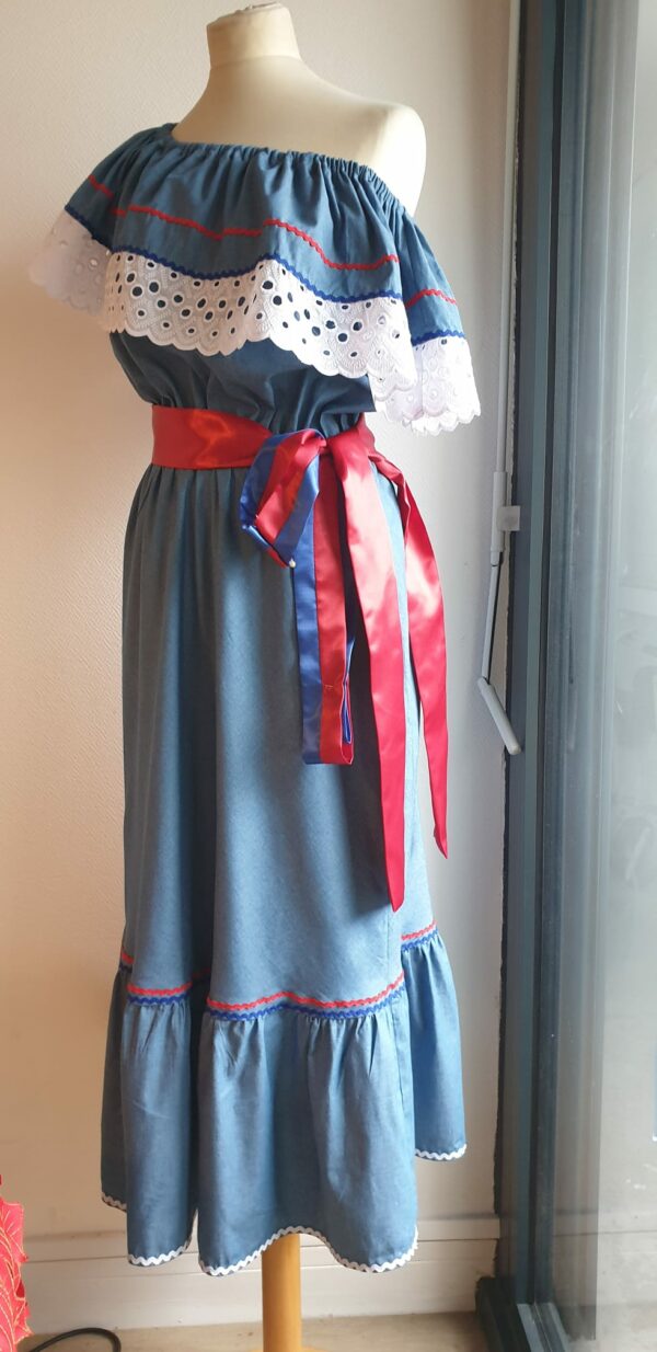 Robe carabela haïtienne bleue clair sur tenue traditionnelle. 2ceintures fournies. Elastique à la taille.