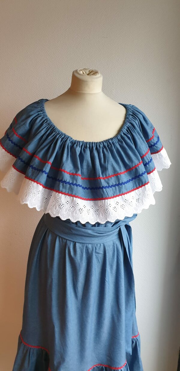 Robe carabela haïtienne bleue clair sur tenue traditionnelle. 2ceintures fournies. Elastique à la taille.