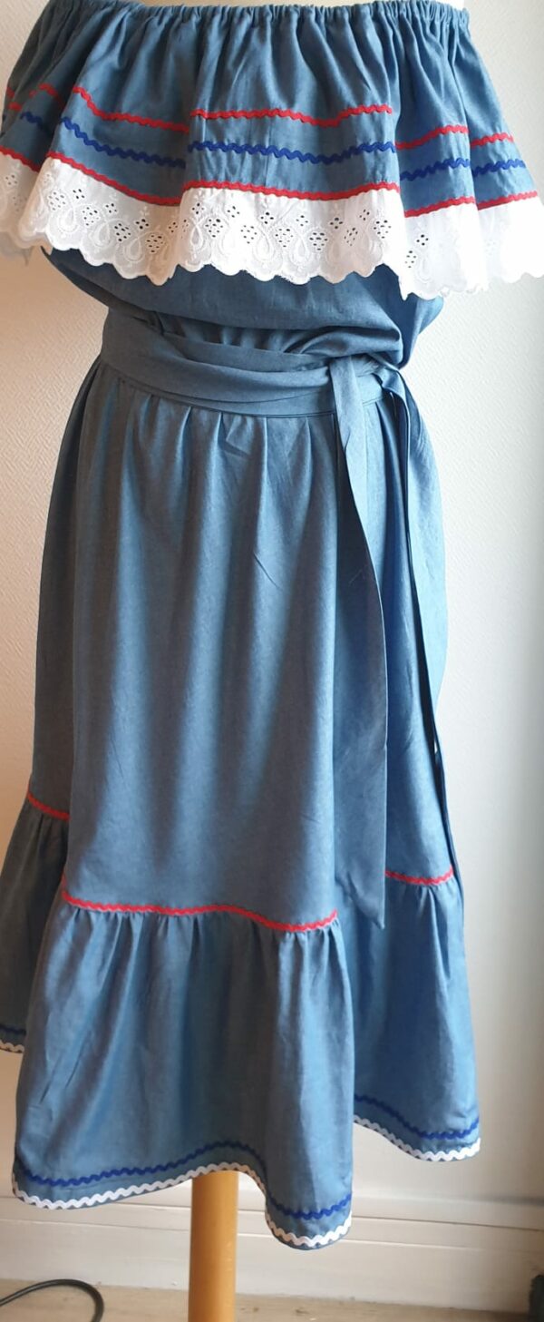 Robe carabela haïtienne bleue clair sur tenue traditionnelle. 2ceintures fournies. Elastique à la taille.