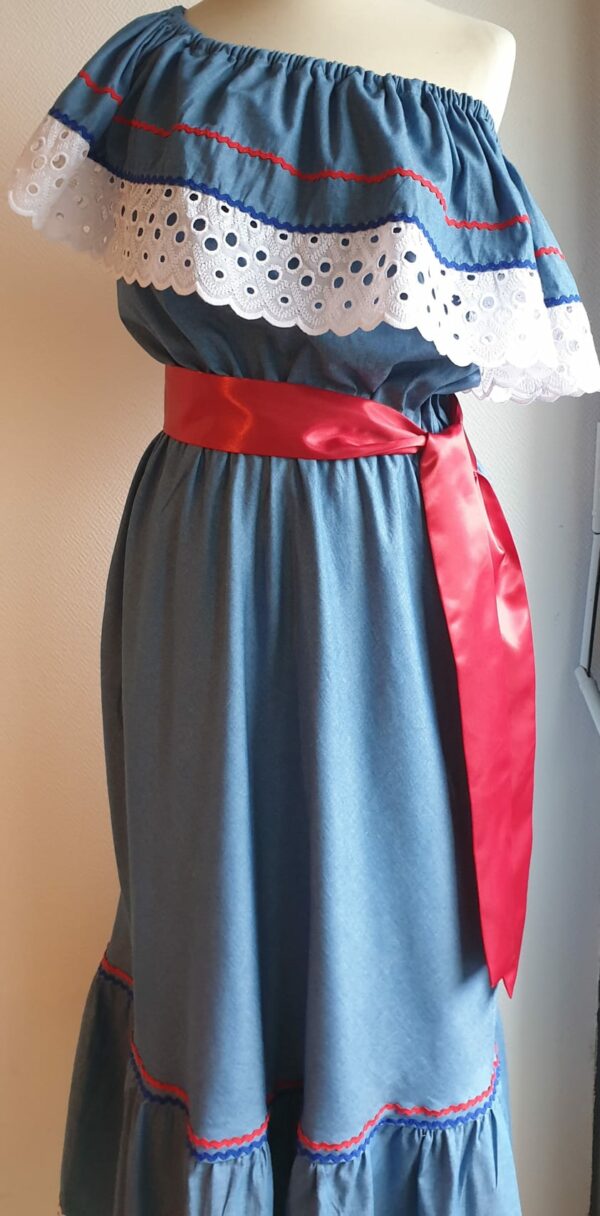 Robe carabela haïtienne bleue clair sur tenue traditionnelle. 2ceintures fournies. Elastique à la taille.