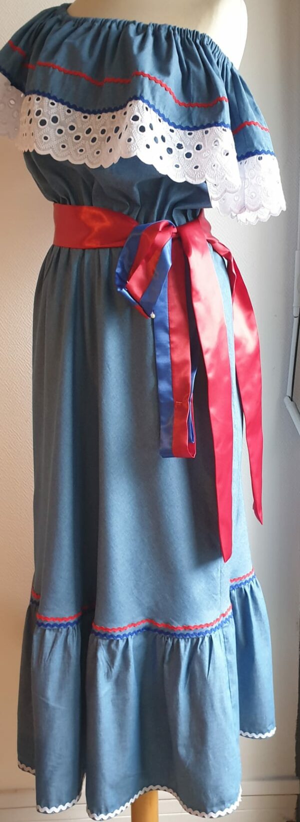 Robe carabela haïtienne bleue clair sur tenue traditionnelle. 2ceintures fournies. Elastique à la taille.