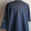 Chemise de couleur bleue foncée assortie du drapeau Haïti sur les deux des trois poches principales, sur une tenue traditionnelle. Une poche miniature supplémentaire a été autorisée sur l'une des deux manches courtes. Une série de trois petits boutons en bois clair est disposée prés le col en V. Le tissu est en carabela pur coton cent pour cent.