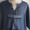 Chemise de couleur bleue foncée assortie du drapeau Haïti sur les deux des trois poches principales, sur une tenue traditionnelle. Une poche miniature supplémentaire a été autorisée sur l'une des deux manches courtes. Une série de trois petits boutons en bois clair est disposée prés le col en V. Le tissu est en carabela pur coton cent pour cent.