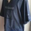 Chemise de couleur bleue foncée assortie du drapeau Haïti sur les deux des trois poches principales, sur une tenue traditionnelle. Une poche miniature supplémentaire a été autorisée sur l'une des deux manches courtes. Une série de trois petits boutons en bois clair est disposée prés le col en V. Le tissu est en carabela pur coton cent pour cent.