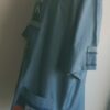 Chemise bleue carabela en tenue traditionnelle haïtienne brodée à la main. Deux poches latérales, une poche brodée centrale, une mini poche sur une manche courte.