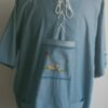 Chemise bleue carabela en tenue traditionnelle haïtienne brodée à la main. Deux poches latérales, une poche brodée centrale, une mini poche sur une manche courte.