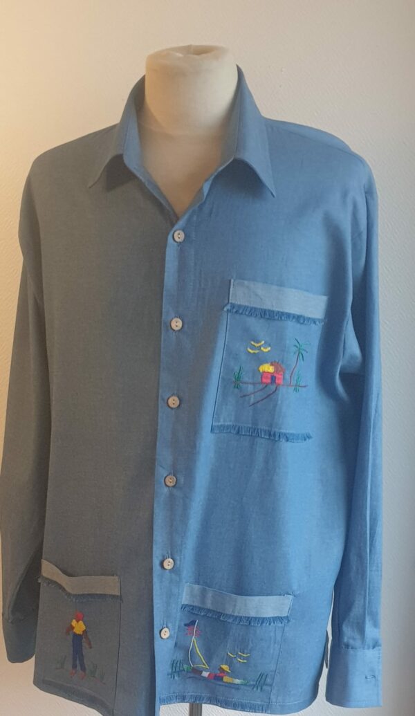 Chemise carabela traditionnelle haïtienne de couleur bleue confectionnée en France. Trois poches brodées main. Ensemble de boutons verticaux et centraux en bois coco. Tissu cent pour cent coton. Création artisanale Anjero