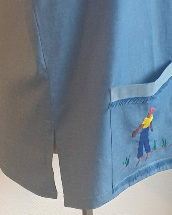 Chemise carabela traditionnelle haïtienne de couleur bleue confectionnée en France. Trois poches brodées main. Ensemble de boutons verticaux et centraux en bois coco. Tissu cent pour cent coton. Création artisanale Anjero