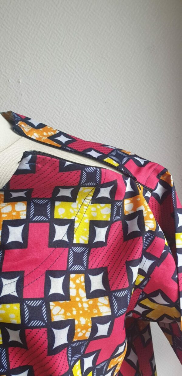 13.5Chemise en tissu coton wax assortie d'un imprimé montrant de jolis symboles arithmétiques jaunes oranges sur fond rouge. Ce modèle est conçu en manches courtes. Une fermeture éclaire à bout fermé subtilement dissimulée est ajoutée sur l'épaule gauche. Elle est faite de nylon souple et d'une tête de fermeture à glissière en métal, solide et durable. La dent de la fermeture à glissière est lisse et ne s'accroche pas, ajoutant ainsi, une touche attractive et supplémentaire à la confection. Taille unique. Ce produit est entièrement confectionné en atelier, en série limitée, par AnjeroCréation.