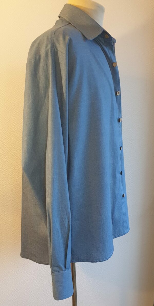 15.3Chemise homme en bleu. Tissu Chambray tout en coton. La coupe soigneusement ceintrée près du corps est accompagnée d'un col boutonné sur le devant. Les boutons sont en bois coco. Différentes tailles. La fabrication est française, imaginée et conçue à Paris par AnjéroCréation.