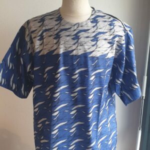 9.1Chemise en tissu coton wax assortie d'un imprimé en vagues océaniques sur fond bleu et inversé sur fond blanc. Ce modèle est conçu en manches courtes. Une fermeture éclaire à bout fermé subtilement dissimulée est ajoutée sur l'épaule gauche. Elle est faite de nylon souple et d'une tête de fermeture à glissière en métal, solide et durable. La dent de la fermeture à glissière est lisse et ne s'accroche pas, ajoutant ainsi, une touche attractive et supplémentaire à la confection. Taille unique. Ce produit est entièrement confectionné, en série limitée, par Anjero. Prix : 39,95€.