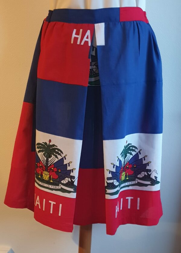 1.2Jupe longue en rouge et bleue avec de chaque côtés le drapeau haïtien. Un grand pli creux suivi des fronces se dessine à l'avant et l'arrière de ce modèle entièrement conçu et réalisé par les ateliers AnjeroCréation à Paris.
