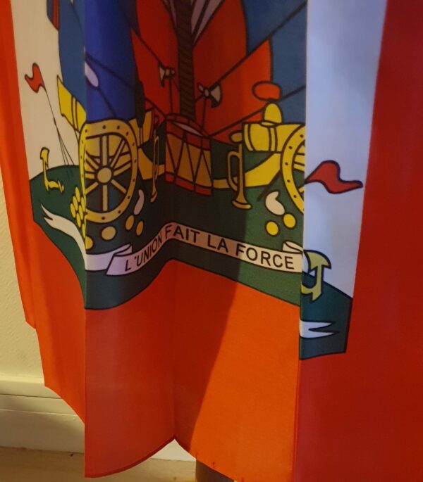 4.2Jupe très longue et plissée en rouge et bleue, avec au centre le grand drapeau haïtien. Le tissu de ce modèle est en polyester. Entièrement conçu et réalisé par les ateliers AnjeroCréation à Paris.