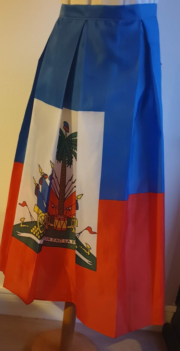 4.3Jupe très longue et plissée en rouge et bleue, avec au centre le grand drapeau haïtien. Le tissu de ce modèle est en polyester. Taille : S, M, L, Xl, XXL. Entièrement conçu et réalisé par les ateliers AnjeroCréation à Paris.