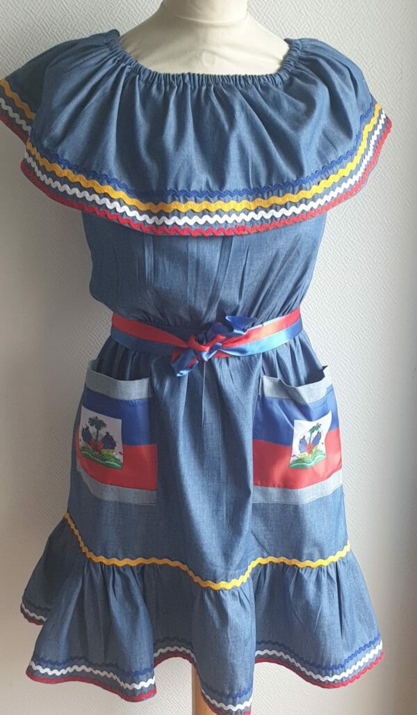 4.3Robe enfant carabela sur une tenue traditionnelle haïtienne. Ce vêtement est élastique à la taille. Il est présenté avec ses deux poches ornées du draapeau d'Haïti et sa ceinture bicolore en rouge et bleue. Taille : 6, 7 ans. Entièrement conçu et réalisé aux ateliers AnjeroCréation à Paris.