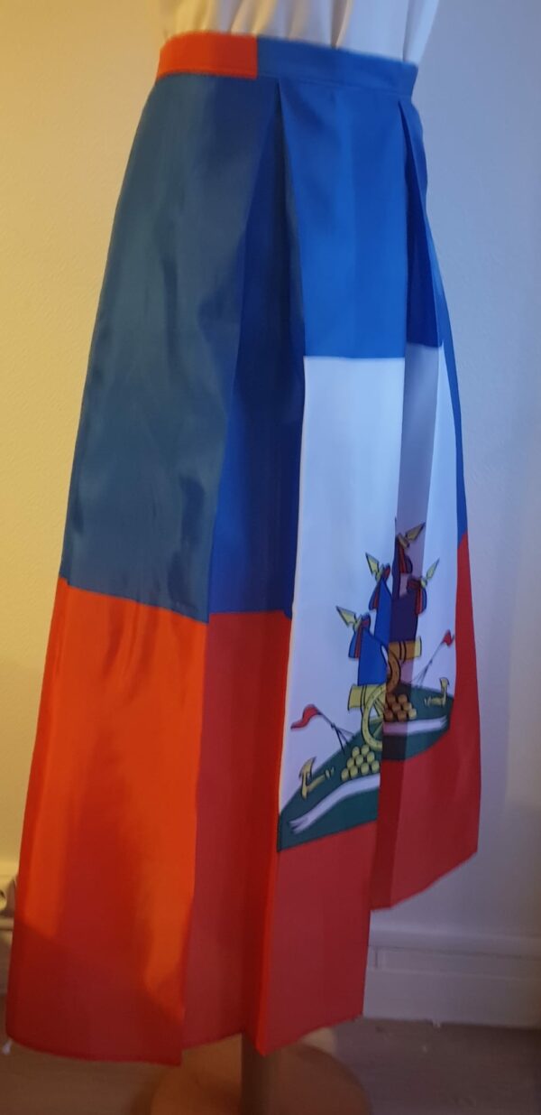 4.4Jupe très longue et plissée en rouge et bleue, avec au centre le grand drapeau haïtien. Le tissu de ce modèle est en polyester. Taille : S, M, L, Xl, XXL. Entièrement conçu et réalisé par les ateliers AnjeroCréation à Paris.