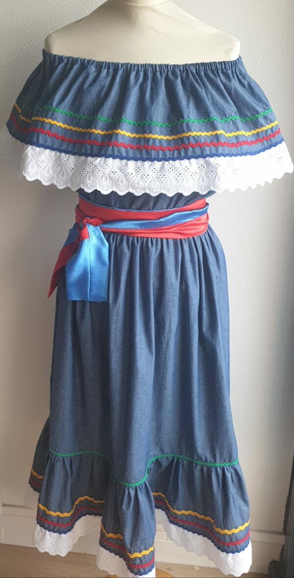 8.1Robe carabela en bleu sur une tenue traditionnelle haïtienne. Très large et élastique à la taille. Zigzag et diversité de couleurs. Dentelle broderie sur le haut ett le bas de la robe. L'ajout d'une ceinture bicolore rouge bleue apporte une touche harmonieuse à la confection. Taille : S, M, L, XL, XXL. Entièrement conçue et réalisée aux ateliers AnjeroCréation à Paris. Prix : 199.95€