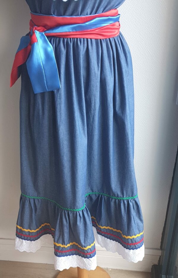 8.3Robe carabela en bleu sur une tenue traditionnelle haïtienne. Très large et élastique à la taille. Zigzag et diversité de couleurs. Dentelle broderie sur le haut ett le bas de la robe. L'ajout d'une ceinture bicolore rouge bleue apporte une touche harmonieuse à la confection. Taille : S, M, L, XL, XXL. Entièrement conçue et réalisée aux ateliers AnjeroCréation à Paris.