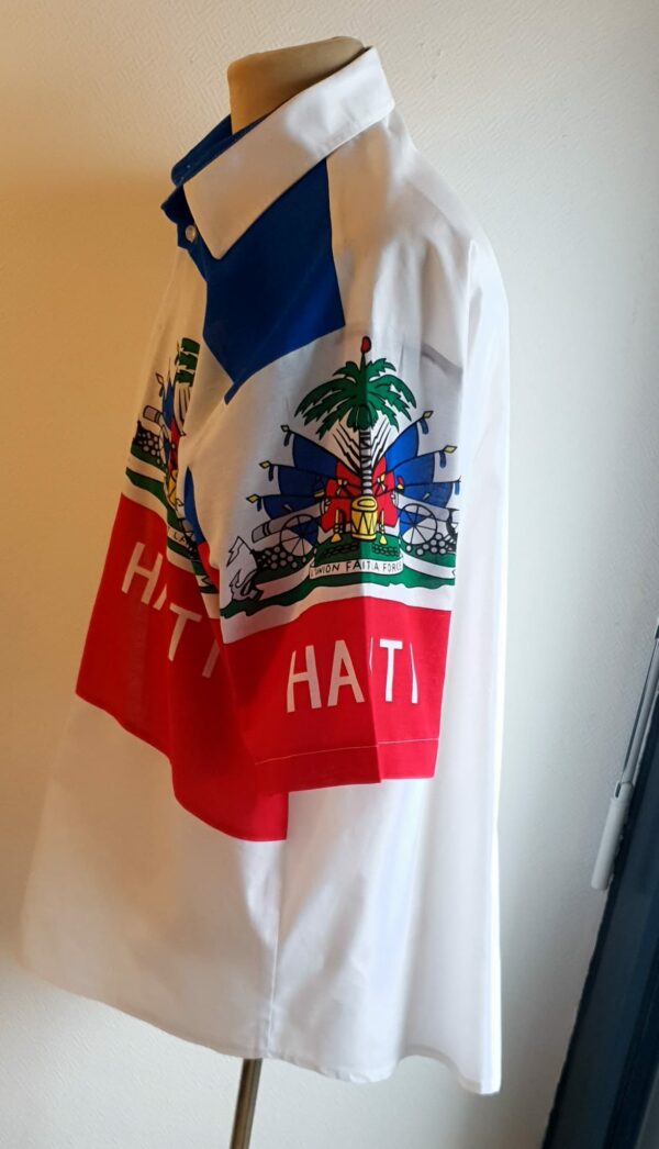 1.2Chemise coupe traditionnelle sur un décor haïtien ornée du drapeau dans un tissu 100 pour 100 coton. Les manches semi-longues apportent un style harmonieux à la confection,  entièrement conçue et réalisée aux ateliers AnjeroCréation à Paris. Taille : S, M, L, XL.