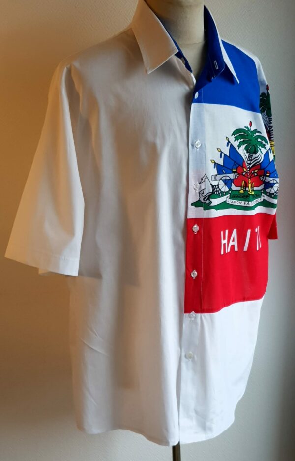 1.3Chemise coupe traditionnelle sur un décor haïtien ornée du drapeau dans un tissu 100 pour 100 coton. Les manches semi-longues apportent un style harmonieux à la confection,  entièrement conçue et réalisée aux ateliers AnjeroCréation à Paris. Taille : S, M, L, XL.