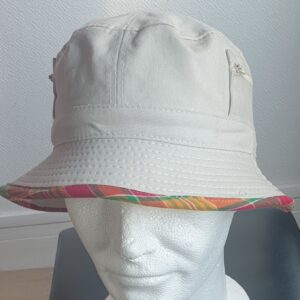 10.1Bob en blanc cassé sur un tissu 100% coton. L'ajout de deux poches latérales zipées apporte une touche harmonieuse à ce couvre-chef. Les finitions en bordure sont en Madras et entièrement conçues puis réalisées aux ateliers AnjeroCréation à Paris.