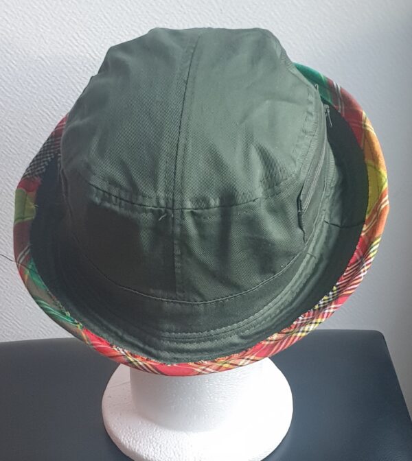 11.2Bob en vert kaki sur un tissu 100% coton. L'ajout de deux poches latérales zipées apporte une touche harmonieuse à ce couvre-chef. Les finitions en bordure sont en Madras et entièrement conçues puis réalisées aux ateliers AnjeroCréation.