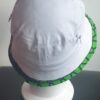 2.2Bob tout en blanc sur un tissu 100% coton. L'ajout de deux poches latérales zipées apporte une touche harmonieuse à la confection. Les finitions en bordure sur le pourtour de ce couvre-chef sont en WAX et réalisées aux ateliers AnjeroCréation.