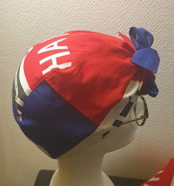 2.2Turban pleine tête orné du drapeau haïtien. Ce couvre-chef apparenté tout à fait original dispose d'une parfaite élasticité à l'arrière pour une adaptation idéale. Ce dernier est conçu et réalisé aux ateliers AnjeroCréation  à Paris.