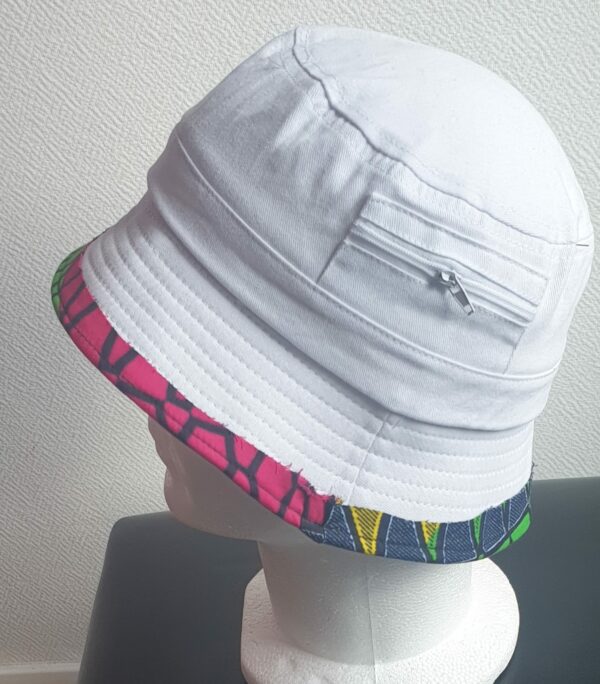 2.3Bob tout en blanc sur un tissu 100% coton. L'ajout de deux poches latérales zipées apporte une touche harmonieuse à la confection. Les finitions en bordure sur le pourtour de ce couvre-chef sont en WAX et réalisées aux ateliers AnjeroCréation.