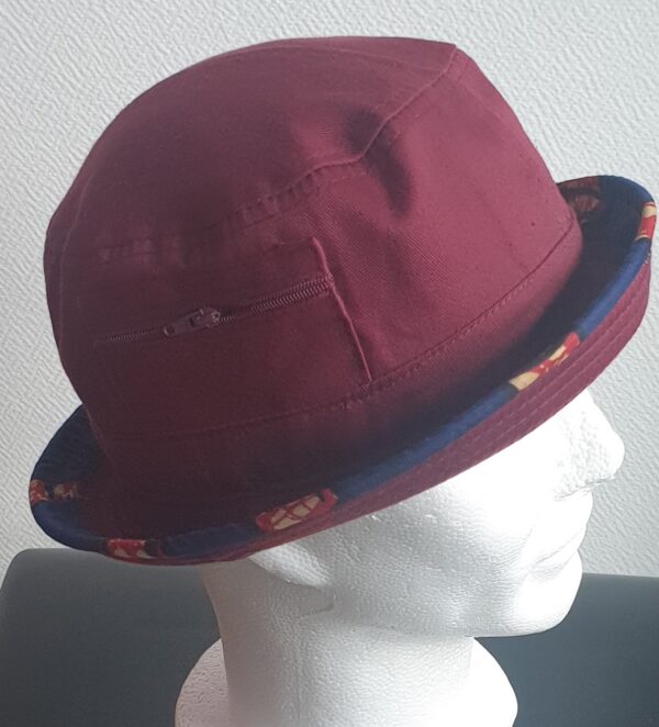3.2Bob tout en rouge grenat sur un tissu 100% coton. L'ajout de deux poches latérales zipées apporte une touche harmonieuse à la confection. Les finitions en bordure sur le pourtour de ce couvre-chef sont en WAX et réalisées aux ateliers AnjeroCréation.