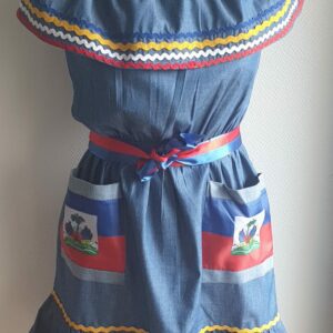 5.1Robe enfant carabela sur une tenue traditionnelle haïtienne en bleu clair. Ce vêtement est élastique à la taille. Il est présenté avec ses deux poches ornées du draapeau d'Haïti et sa ceinture bicolore en rouge et bleue. Entièrement conçu et réalisé aux ateliers AnjeroCréation à Paris.