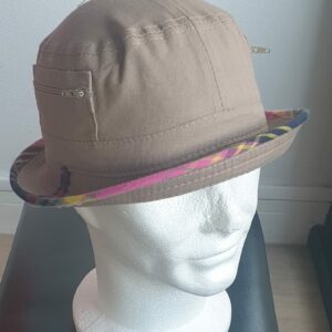 6.1Bob en marron clair sur un tissu 100% coton.  L'ajout de deux poches latérales zipées apporte une touche harmonieuse à ce couvre-chef. Les finitions en bordure sont en Madras et entièrement conçues puis réalisées aux ateliers AnjeroCréation à Paris. Taille : 55, 57, 59. Prix 15,95€.
