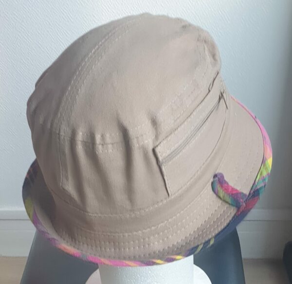 6.4Bob en marron clair sur un tissu 100% coton.  L'ajout de deux poches latérales zipées apporte une touche harmonieuse à ce couvre-chef. Les finitions en bordure sont en Madras et entièrement conçues puis réalisées aux ateliers AnjeroCréation à Paris.