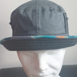 7.1Bob gris clair sur un tissu 100% coton. L'ajout de deux poches latérales zipées apporte une touche harmonieuse à ce couvre-chef. Les finitions en bordure sont en Madras et entièrement conçues puis réalisées aux ateliers AnjeroCréation à Paris.