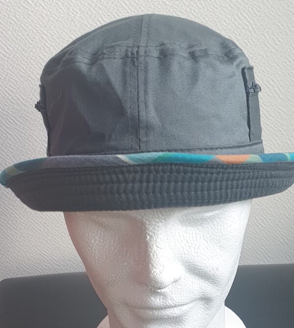7.1Bob gris clair sur un tissu 100% coton. L'ajout de deux poches latérales zipées apporte une touche harmonieuse à ce couvre-chef. Les finitions en bordure sont en Madras et entièrement conçues puis réalisées aux ateliers AnjeroCréation à Paris.