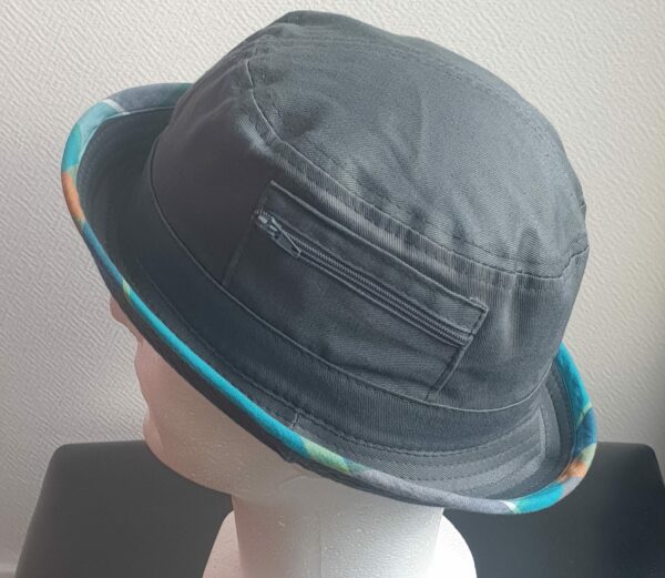 7.4Bob gris clair sur un tissu 100% coton. L'ajout de deux poches latérales zipées apporte une touche harmonieuse à ce couvre-chef. Les finitions en bordure sont en Madras et entièrement conçues puis réalisées aux ateliers AnjeroCréation à Paris.