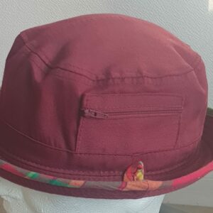 9.1Bob en rouge grenat sur un tissu 100% coton. L'ajout de deux poches latérales zipées apporte une touche harmonieuse à ce couvre-chef. Les finitions en bordure sont en Madras et entièrement conçues puis réalisées aux ateliers AnjeroCréation à Paris.