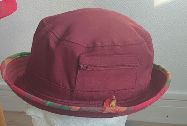 9.1Bob en rouge grenat sur un tissu 100% coton. L'ajout de deux poches latérales zipées apporte une touche harmonieuse à ce couvre-chef. Les finitions en bordure sont en Madras et entièrement conçues puis réalisées aux ateliers AnjeroCréation à Paris.