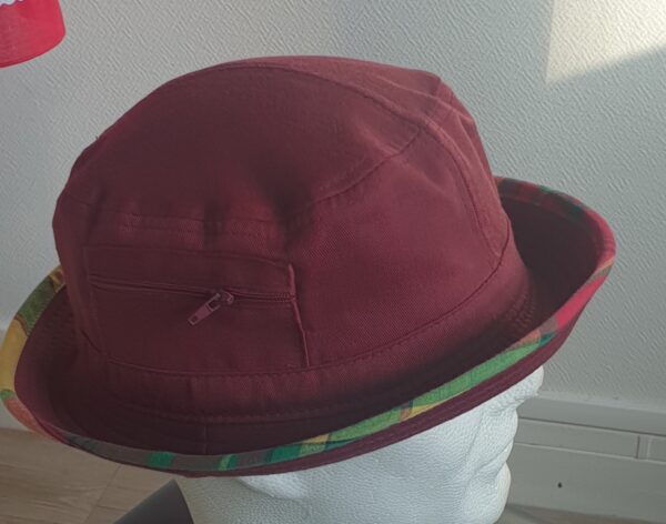 9.2Bob en rouge grenat sur un tissu 100% coton. L'ajout de deux poches latérales zipées apporte une touche harmonieuse à ce couvre-chef. Les finitions en bordure sont en Madras et entièrement conçues puis réalisées aux ateliers AnjeroCréation à Paris.