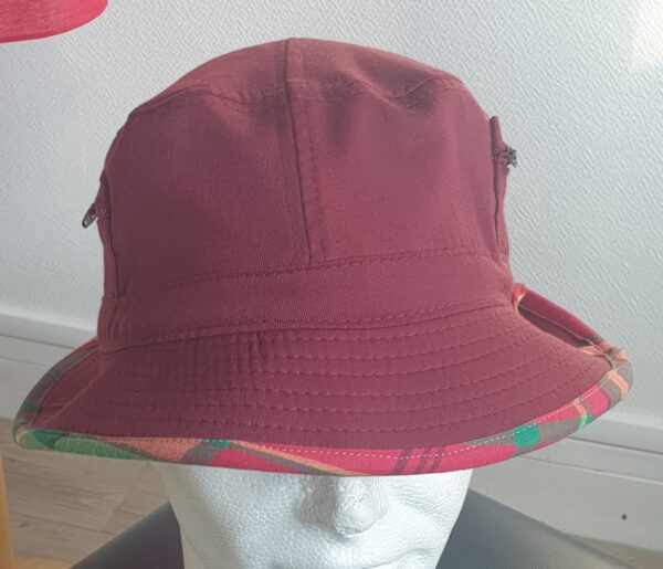 9.3Bob en rouge grenat sur un tissu 100% coton. L'ajout de deux poches latérales zipées apporte une touche harmonieuse à ce couvre-chef. Les finitions en bordure sont en Madras et entièrement conçues puis réalisées aux ateliers AnjeroCréation à Paris.