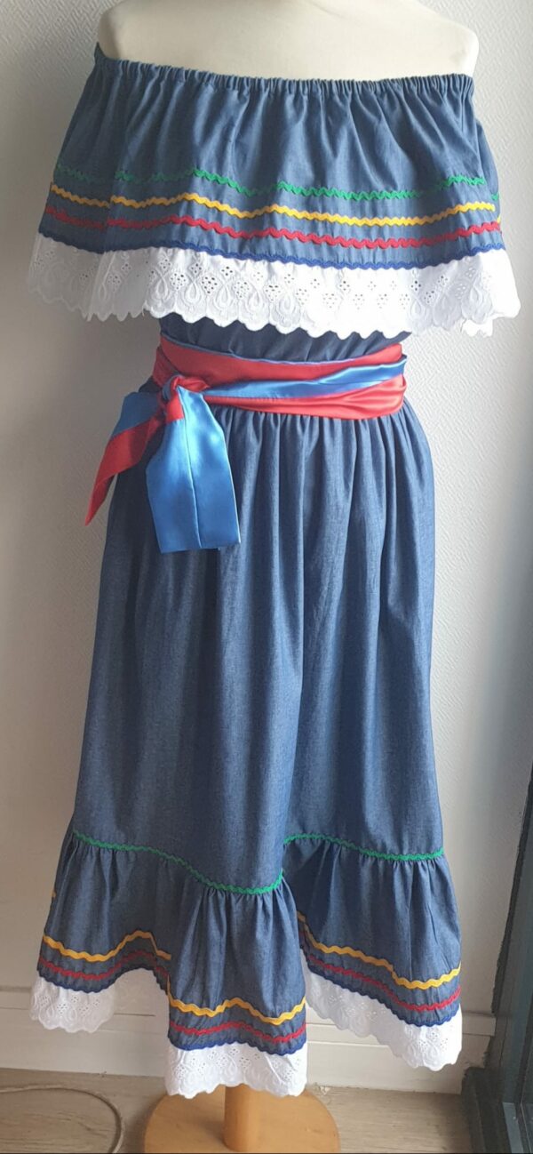 9.3Robe carabela sur une tenue traditionnelle haïtienne. Le style est très évasé avec une parfaite élasticité à la taille. Les zigzags comportent une large diversité de couleurs. Une broderie en dentelle est confectionnée sur le haut et le bas de la robe. L'adjonction d'une ceinture bicolore rouge bleue vient apporter une touche harmonieuse au vêtement. Ce produit est entièrement conçu et réalisé aux ateliers AnjeroCréation à Paris.